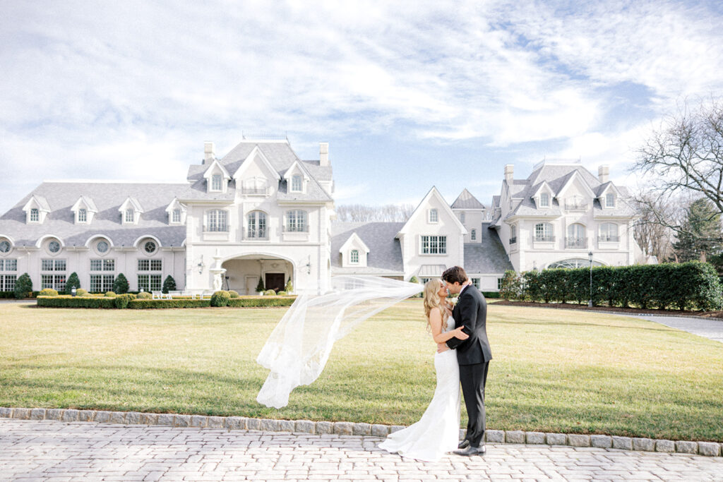Bride and groom pose in the cobblestone driveway in front of the Park Chateau wedding venue East Brunswick NJ | Photo by Lindsey Ford Photography