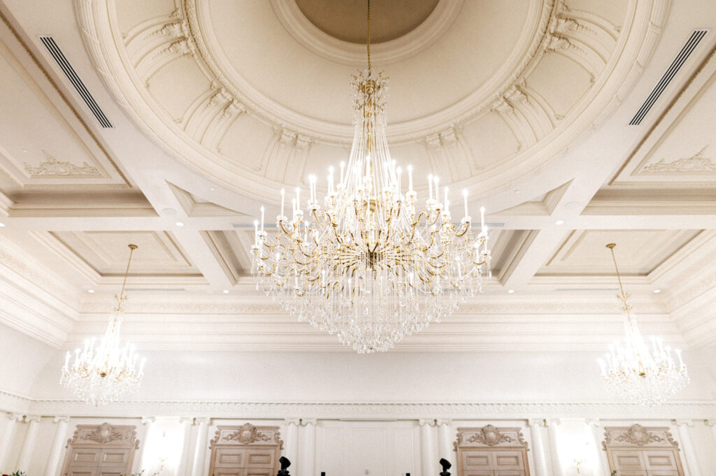 Large crystal chandelier hangs from a carved recessed ceiling in the ballroom at the Park Chateau