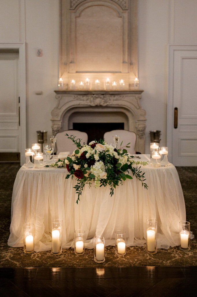 A sweetheart table laid with floating candles and florals in the ballroom at the Park Chateau