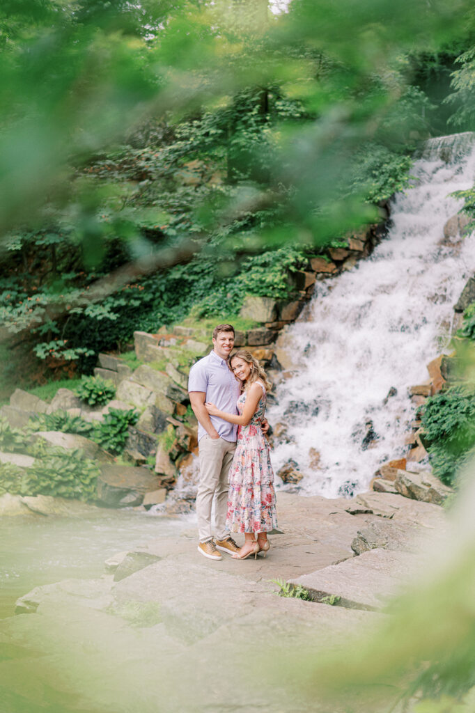 Couple poses at the base of a waterfall in Longwood Gardens | Longwood Gardens Engagement Photo Session in Philadelphia by Lindsey Ford Photography