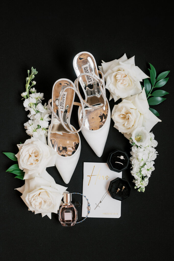 Flat lay of black and white wedding details and white Badgley Mischka bridal shoes at The Cork Factory Hotel