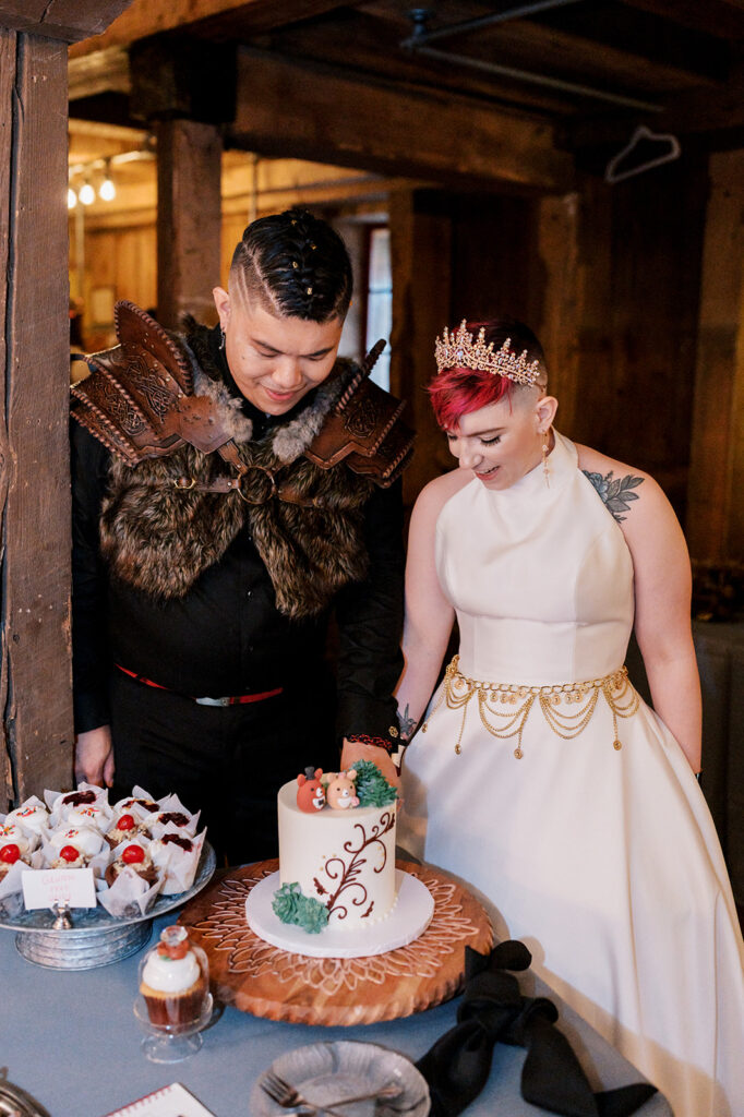 Bride and groom dressed in Renaissance Faire attire look at the dessert table at their wedding reception