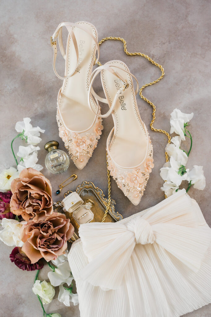 Pointed toe heels from Bella Belle sit next to cream colored clutch from Loeffler Randall