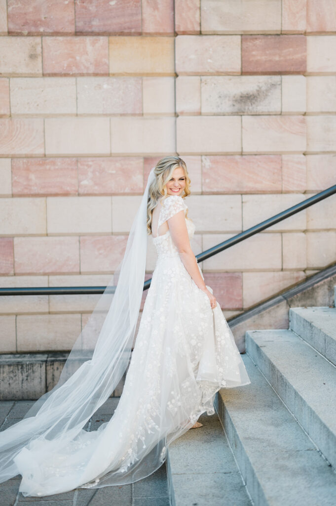 Bride in a white dress and long veil ascends a cement staircase in downtown Lancaster PA 