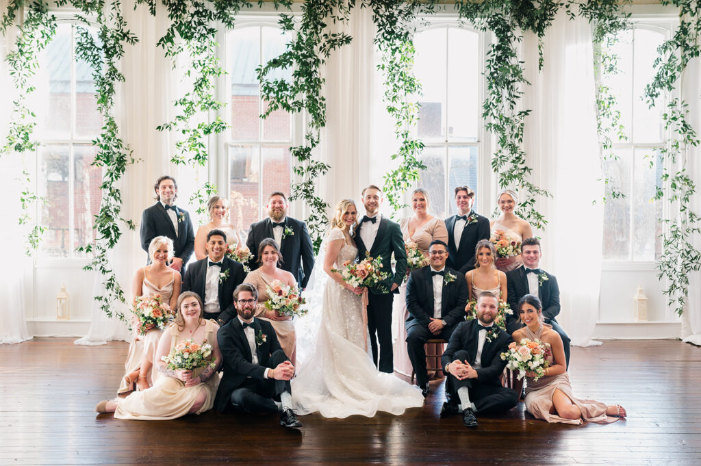Bride and groom are surrounded by their bridal party of eight groomsmen and eight bridesmaids