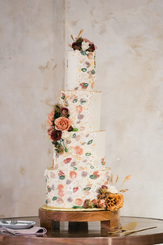 Four tier wedding cake with flower petals painted in icing 