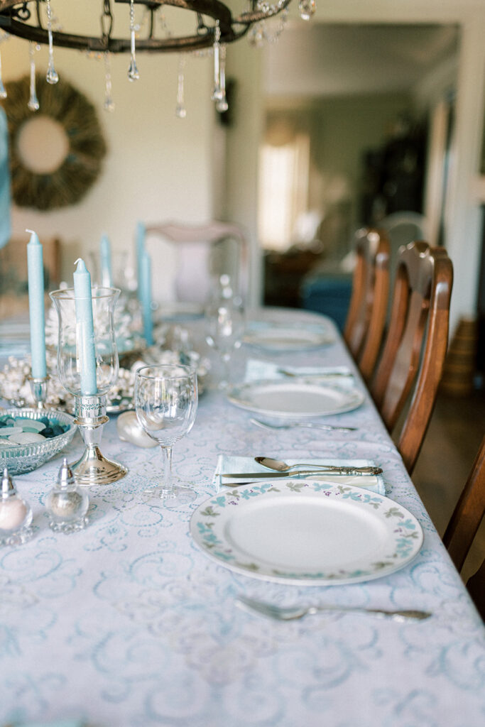 Dining table is set with blue coastal themed centerpiece and blue and white linens