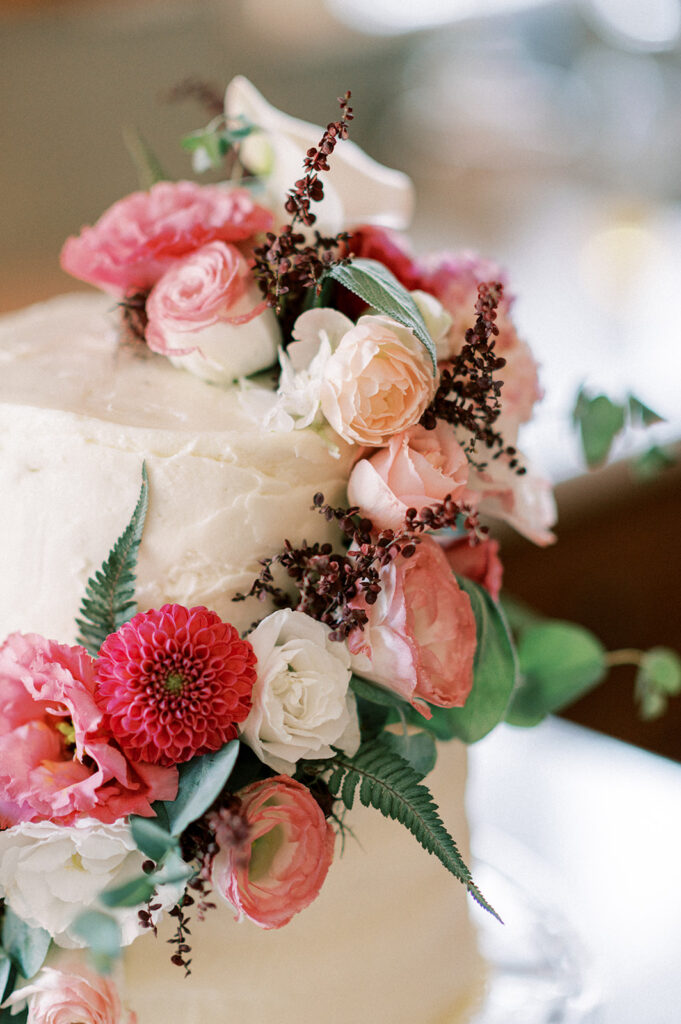 Two-tiered white wedding cake decorated with pink and white florals