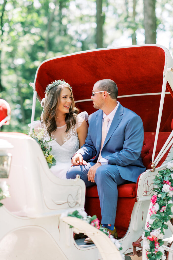 Bride and groom ride in a horse drawn carriage lined with a red velvet seat and interior