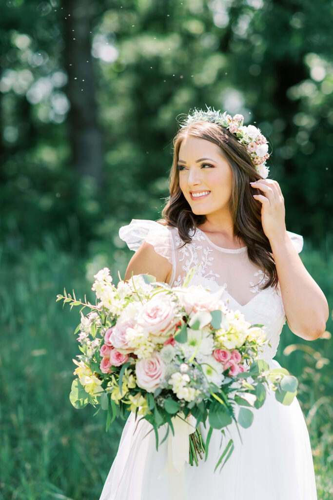 Bride holds a white, green, and pink bouquet as she stands posing for bridal portraits