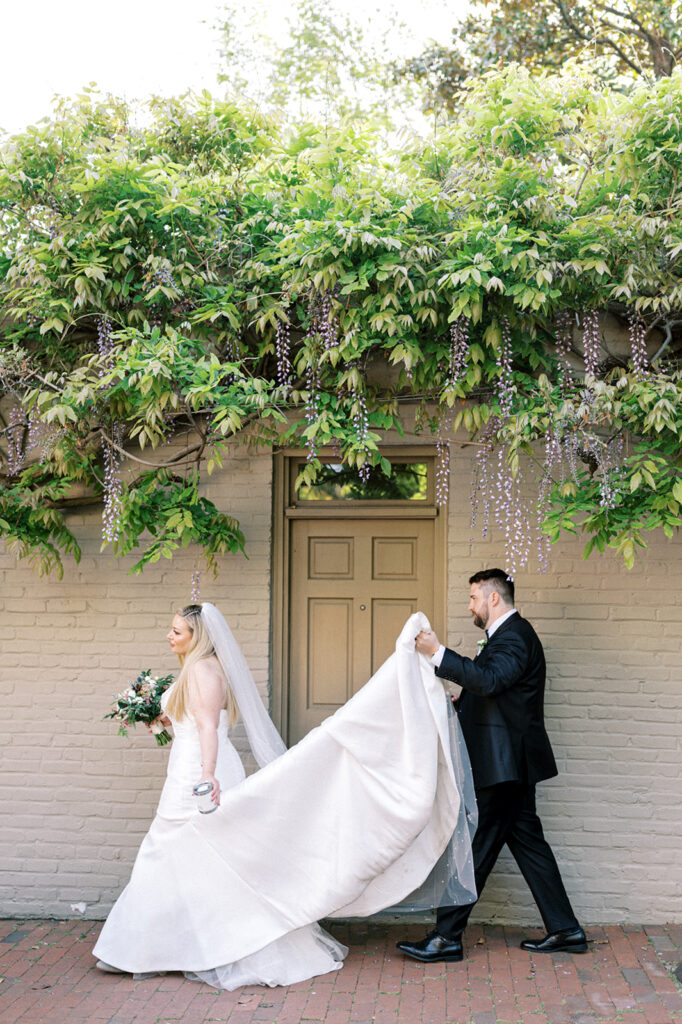 Bride and groom walk underneath a hedge of hanging wisteria in Washington DC