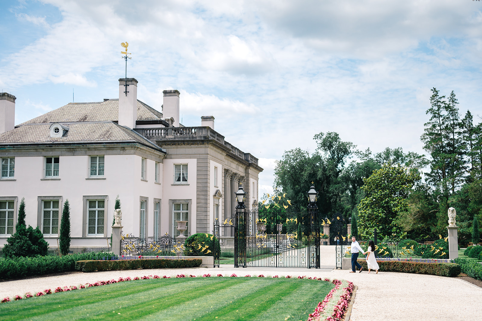 Wide view of the Nemours Estate house surrounded by a manicured lawn and garden path and wrought iron fence