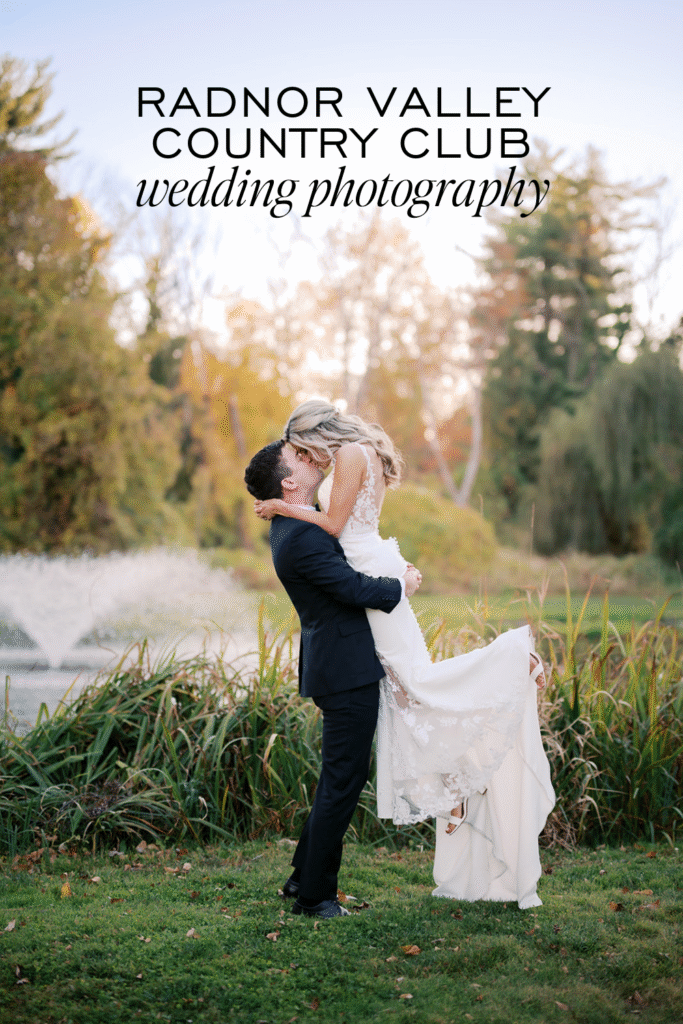 Groom lifts bride in front of a pond with a fountain at the Radnor Valley Country Club during their couples portraits