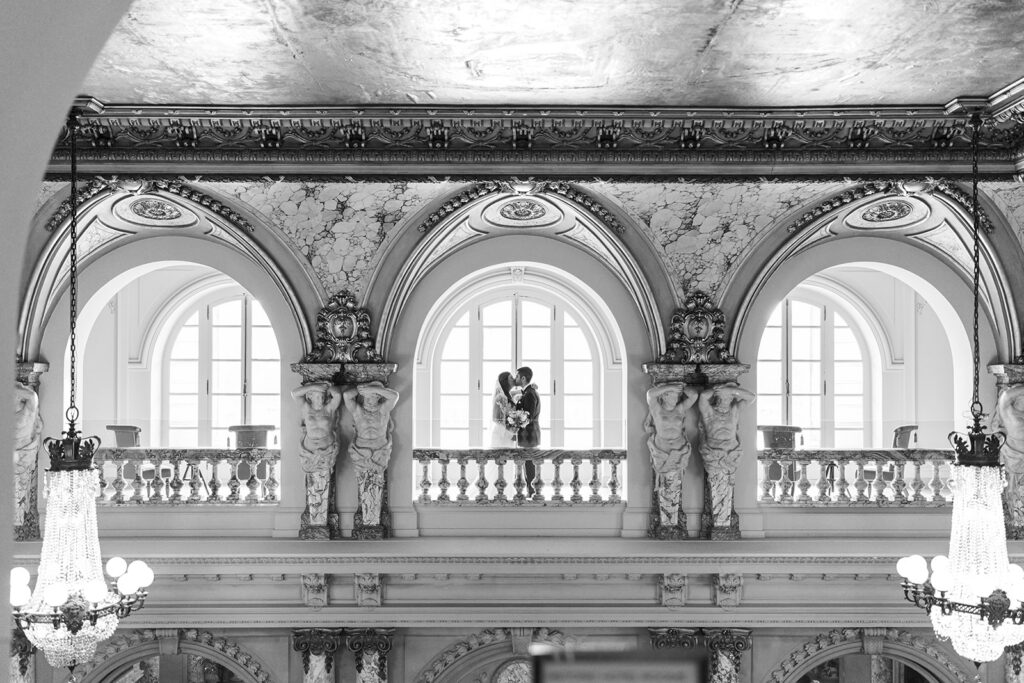 Bride and groom kiss under an arched cutout in the second story gallery at Elkins Estate, photographed by Lindsey Ford Photography