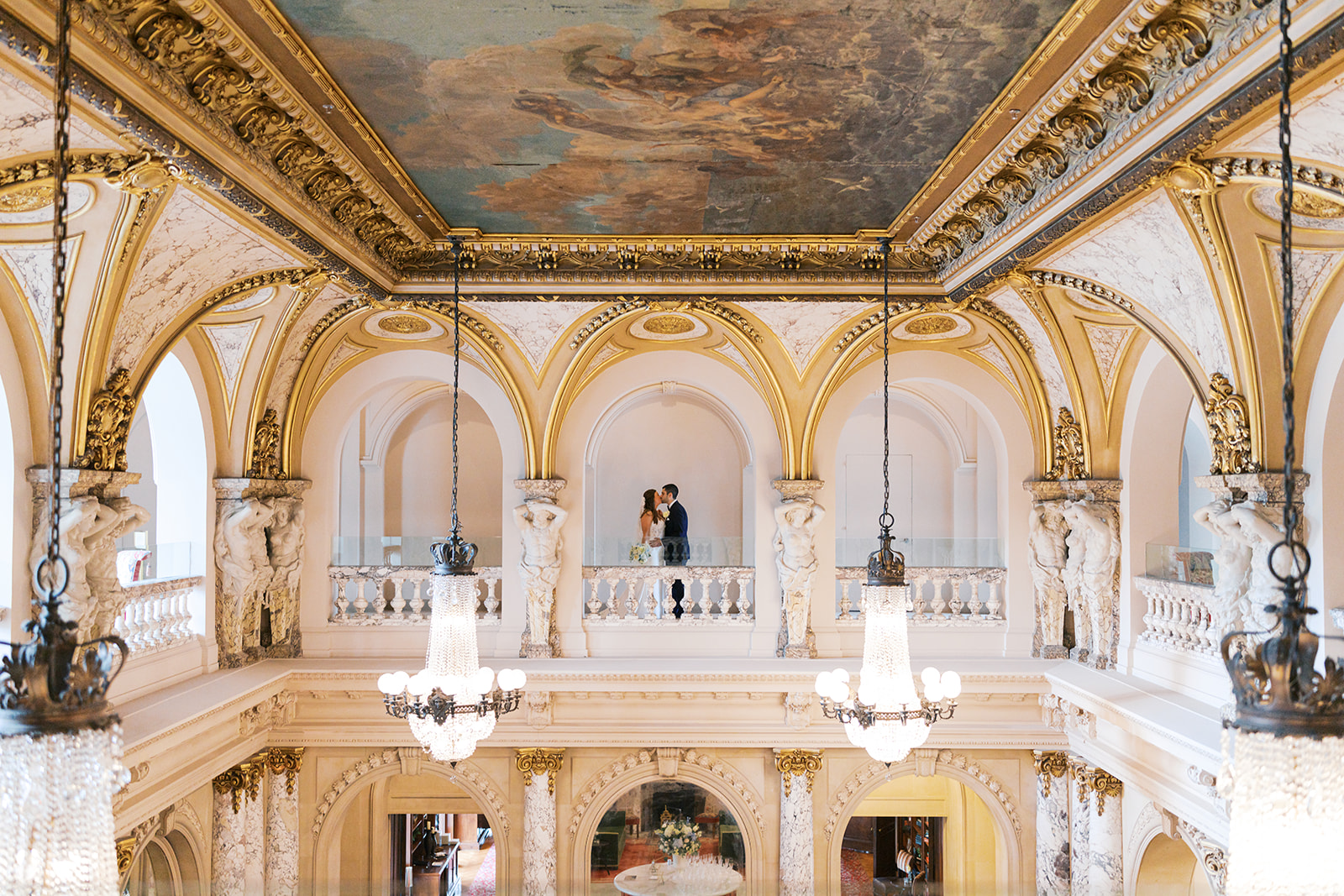 Bride and groom kiss under an arched cutout and ornate painted ceiling in the second story gallery at Elkins Estate, photographed by Lindsey Ford Photography