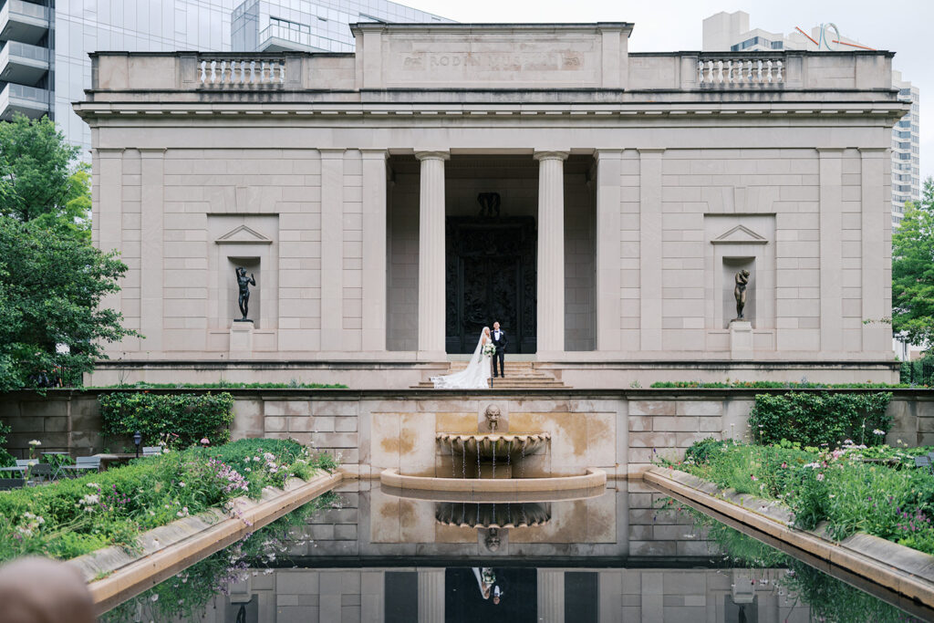 Couple stands above the outdoor fountain in front of the Rodin museum in Philadelphia 