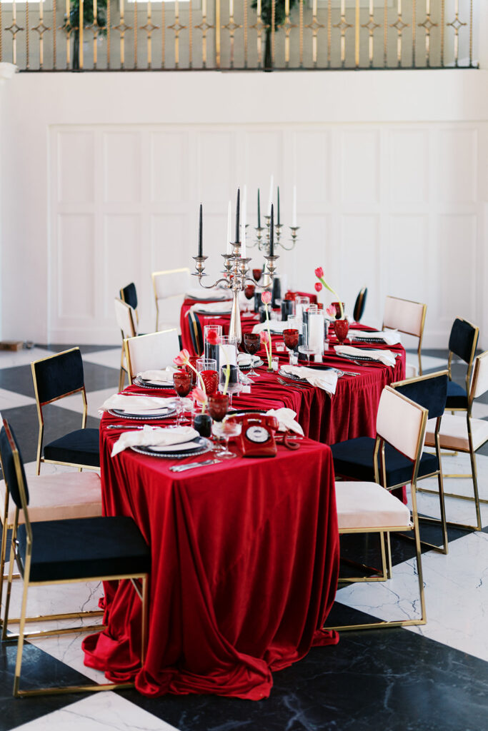 Curved banquet table covered in red linen and black and white wedding reception decor surrounded by black and white chairs at Elkins Estate | Lindsey Ford Photography