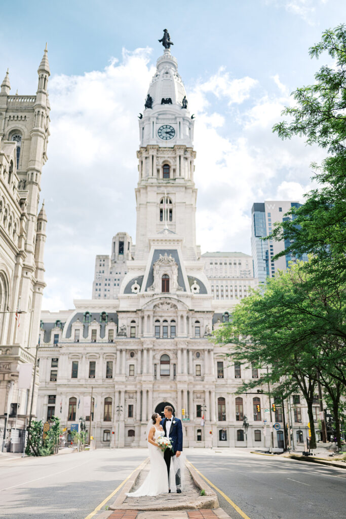 Bride and groom pose in the middle of the road in front of Philadelphia City Hall building | Lindsey Ford Photography