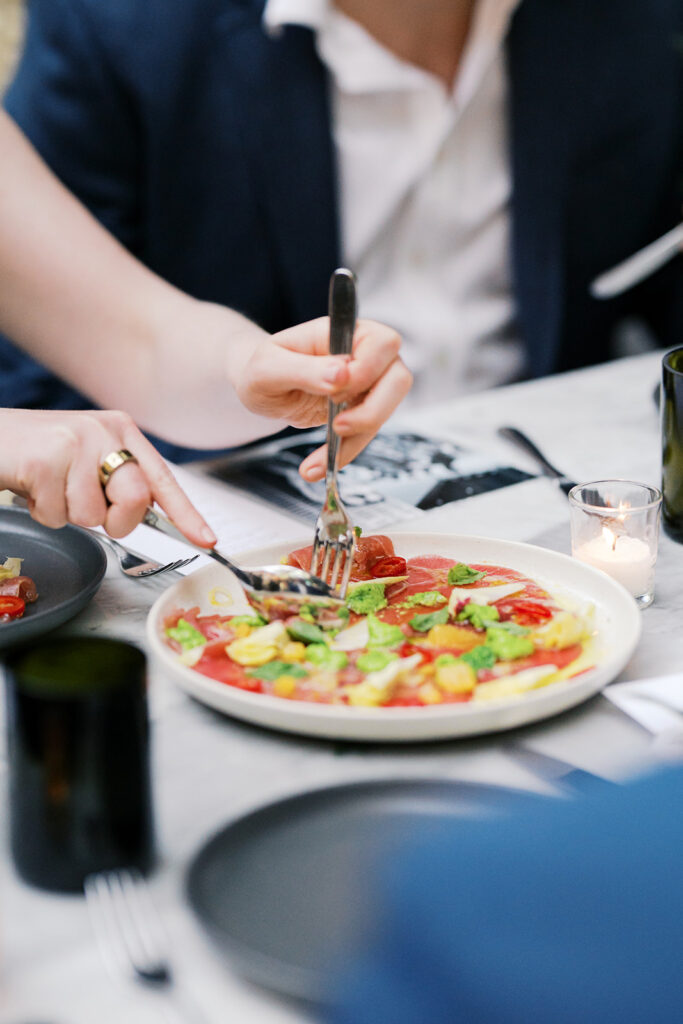 Close up of hands cutting tuna carpaccio on a white plate