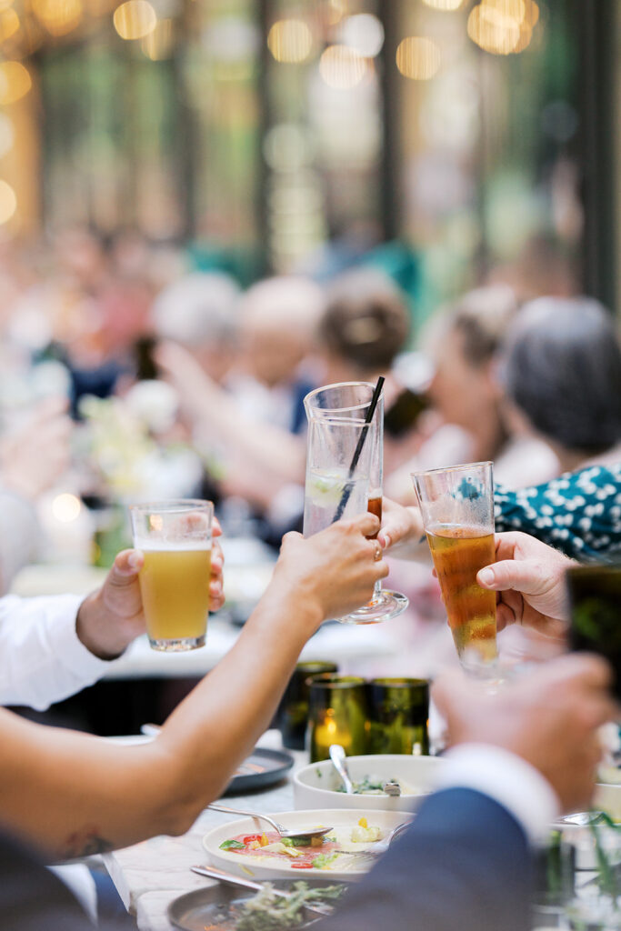 Close up of wedding guests clinking glasses of signature cocktail during a wedding at Osteria Philly