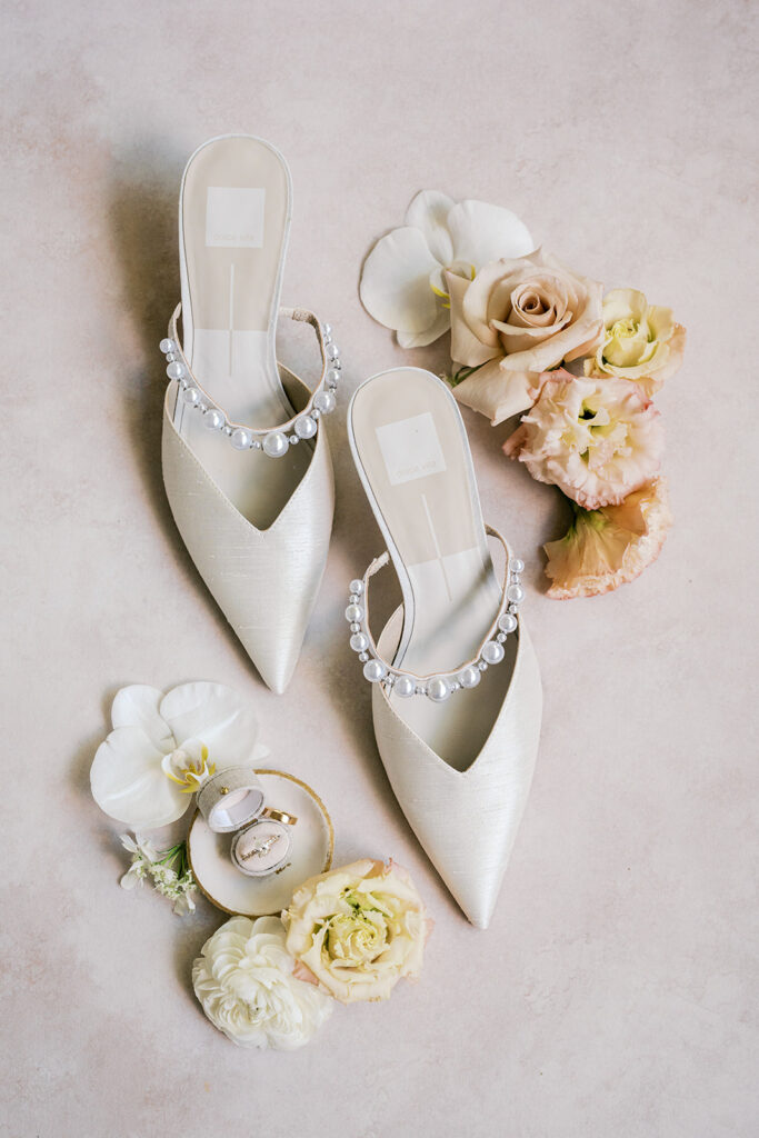 Pointed toe white bridal kitten heels surrounded by loose pastel florals