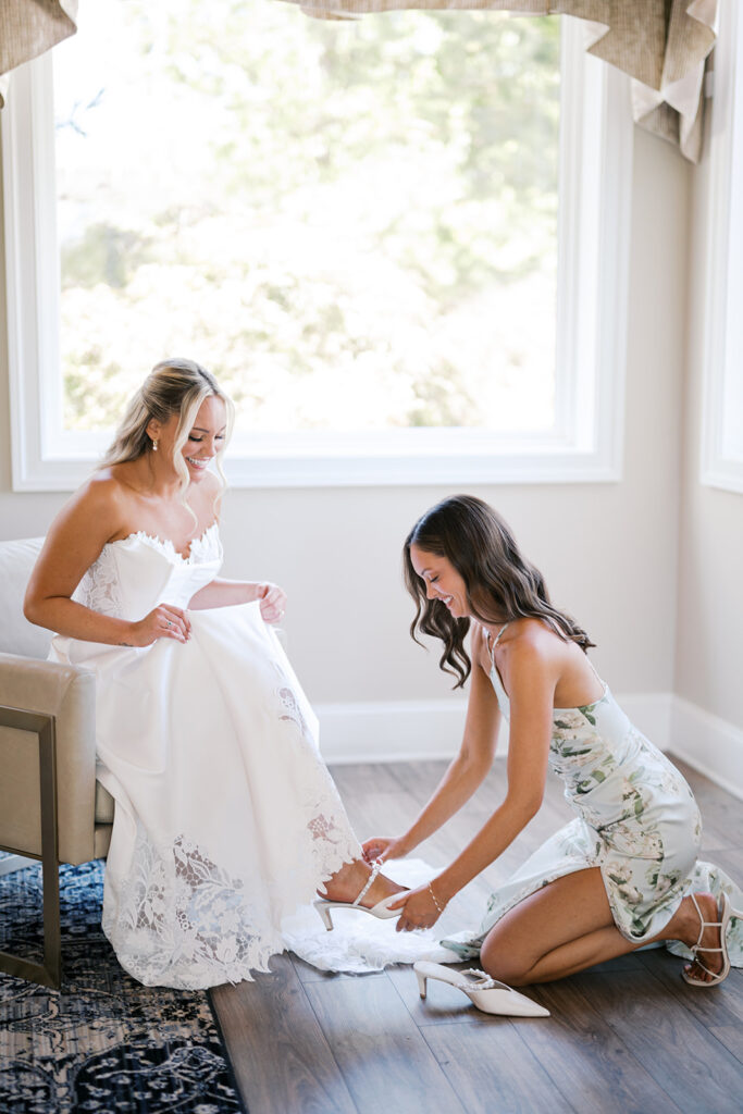 Bridesmaid helps bride put on her shoes