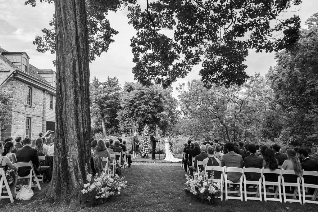 Black and white photo of an outdoor wedding ceremony at Bartram's Garden photographed by Lindsey Ford Photography in Philadelphia