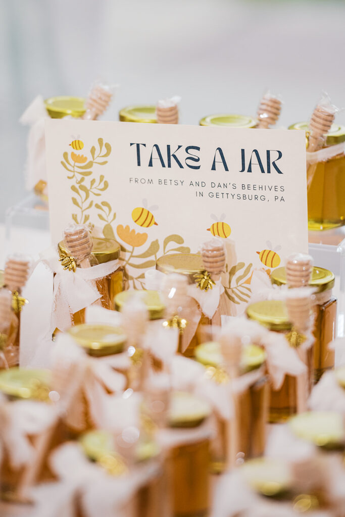 Sign reading "Take a Jar" sits on a table full of small jars of honey
