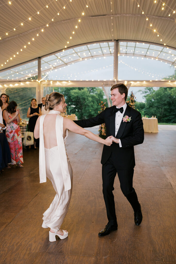 Bride and groom dance under market lights inside their reception tent at Bartram's Garden