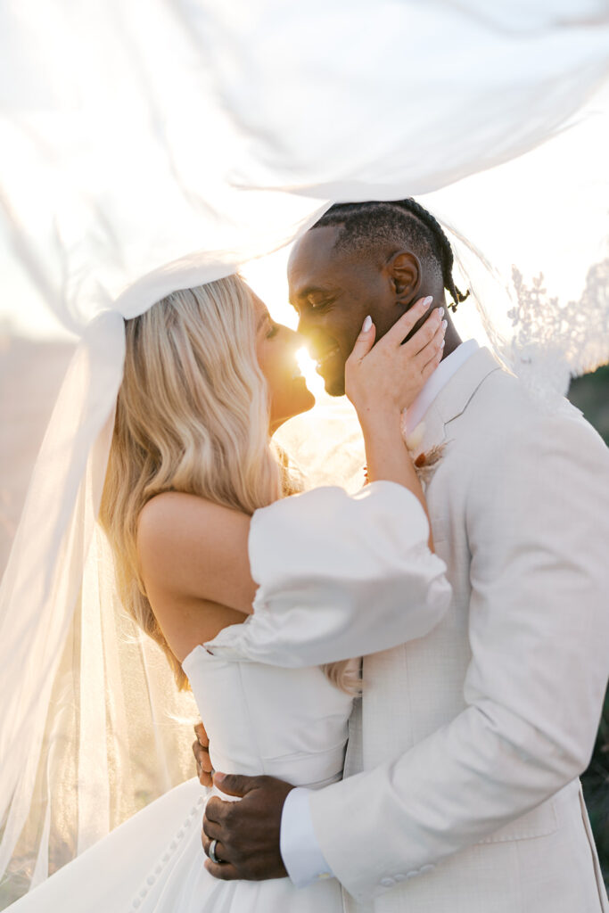 Bride and groom kiss with the setting sun casting a warm hazy glow around them at Terrain Gardens at DelVal
