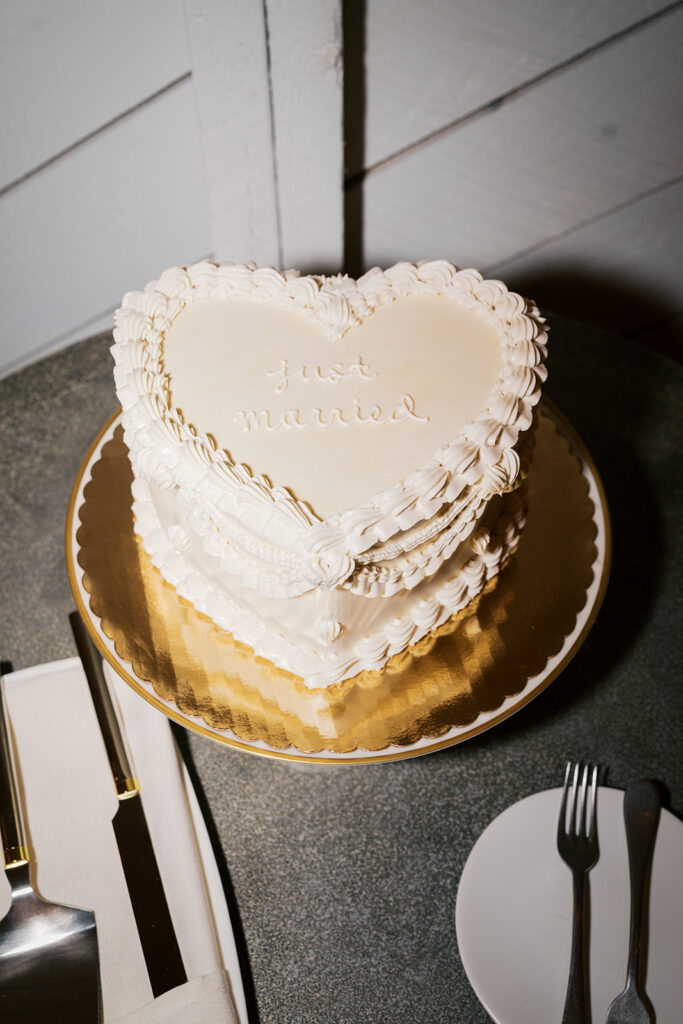 Vintage inspired buttercream piped heart shaped wedding cake on a gold charger reads Just Married