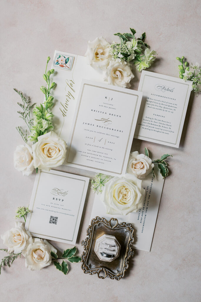 Elegant wedding invitation suite flatlay with white roses and gold calligraphy Lake House Inn Pennsylvania