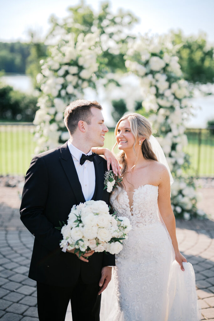 Romantic bride and groom portrait with white floral ceremony arch lakefront backdrop Lake House Inn Perkasie PA