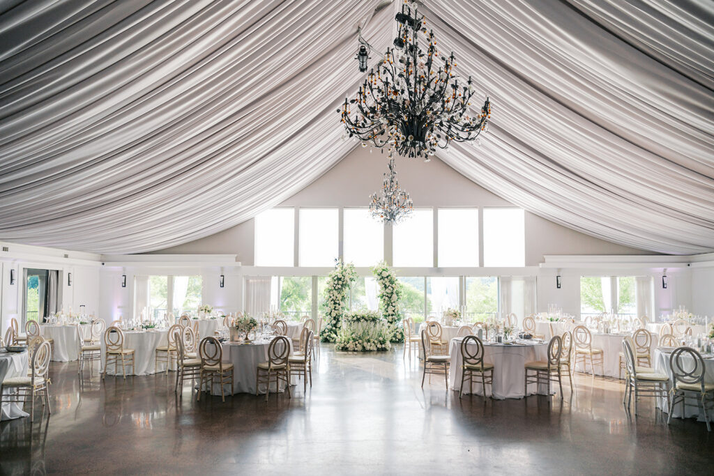 Stunning Lake House Inn pavilion interior with dramatic ceiling draping crystal chandeliers and white floral installations