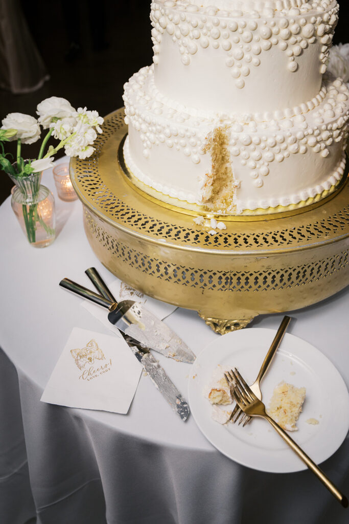 Elegant white pearl wedding cake cutting detail with gold serving utensils Lake House Inn Perkasie PA reception