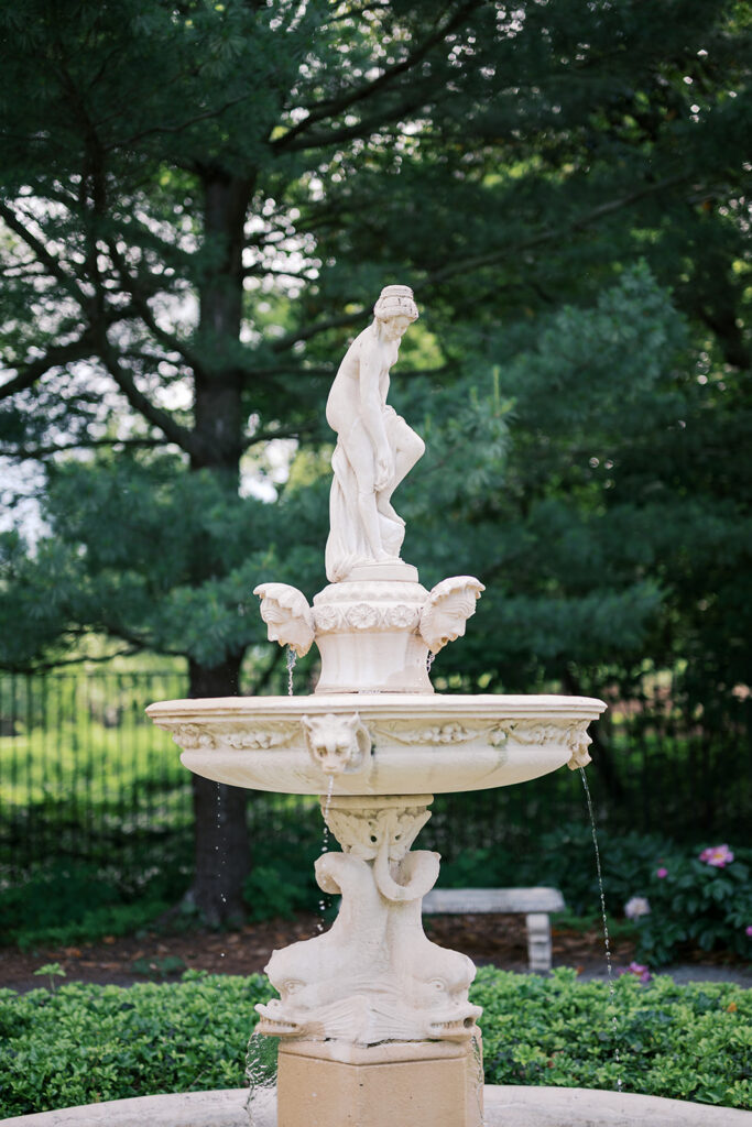 Ornate white tiered fountain with female sculpture at Marian Coffin Gardens