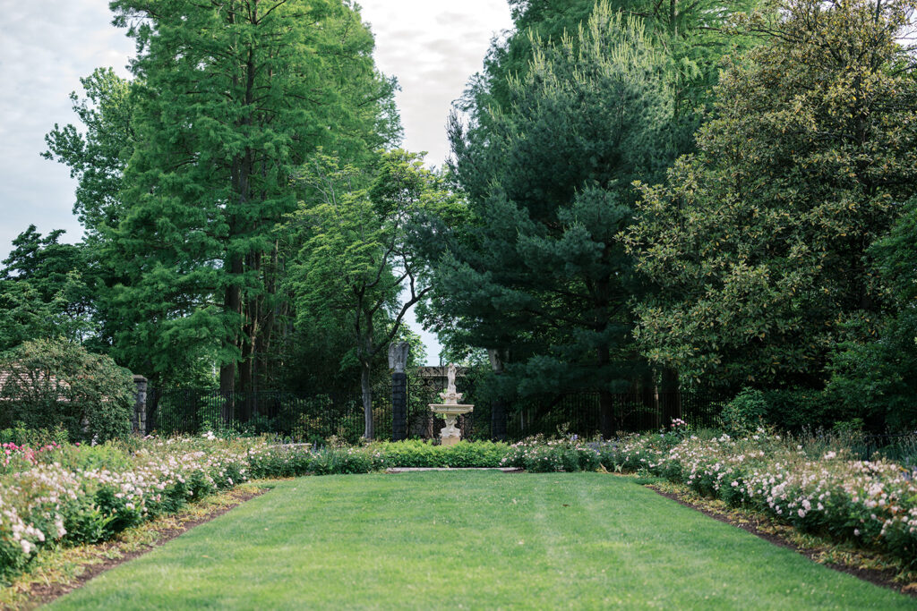 Wide view of the formal lawn and flower borders leading to the iron gates and fountain at Marian Coffin Gardens DE engagement session location