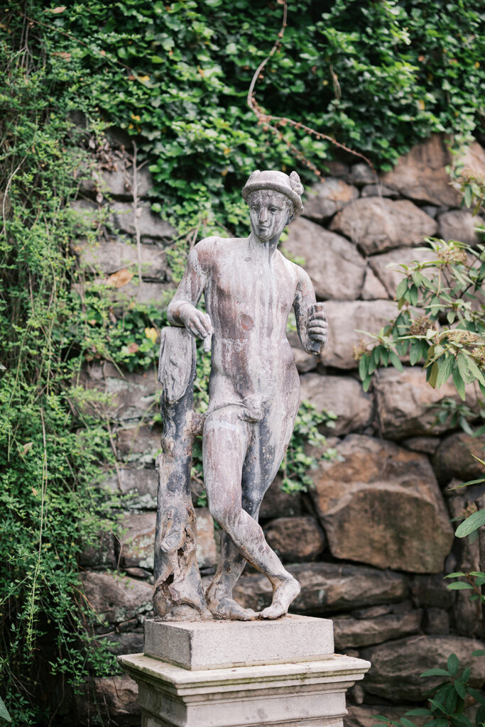 Weathered classical stone statue surrounded by ivy wall at Marian Coffin Gardens engagement session location in Delaware