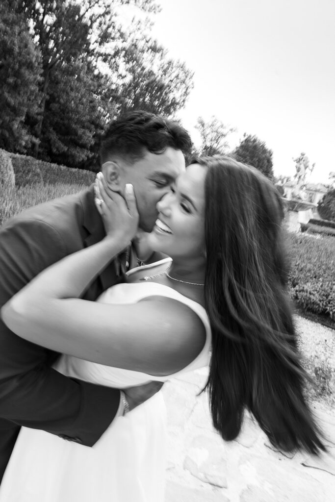 Romantic couples photography black and white artistic swirl couple laughing during cheek kiss at Nemours Estate formal garden Wilmington Delaware