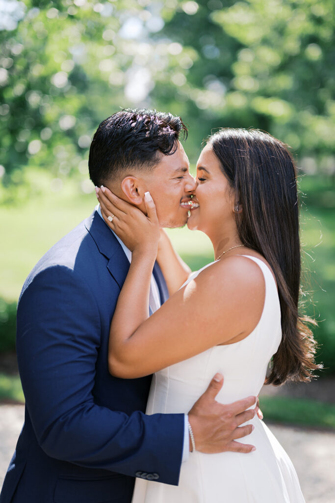 Romantic couples photography couple kissing at Nemours Estate in white sleeveless dress and navy suit summer engagement photo outfits Wilmington