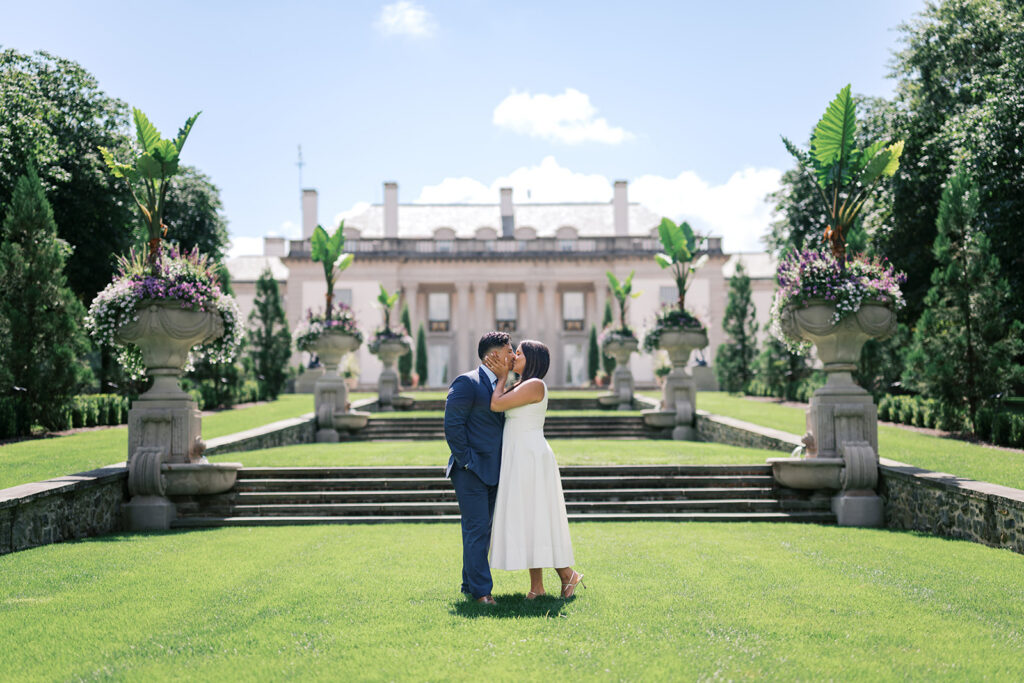 Nemours Estate engagement session couple kissing on the lawn with the Nemours mansion in Wilmington Delaware summer engagement photos