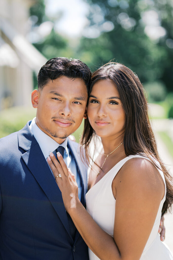 Nemours Estate engagement session close portrait with emerald cut engagement ring detail woman in white v-neck dress and navy suit engagement photo ideas
