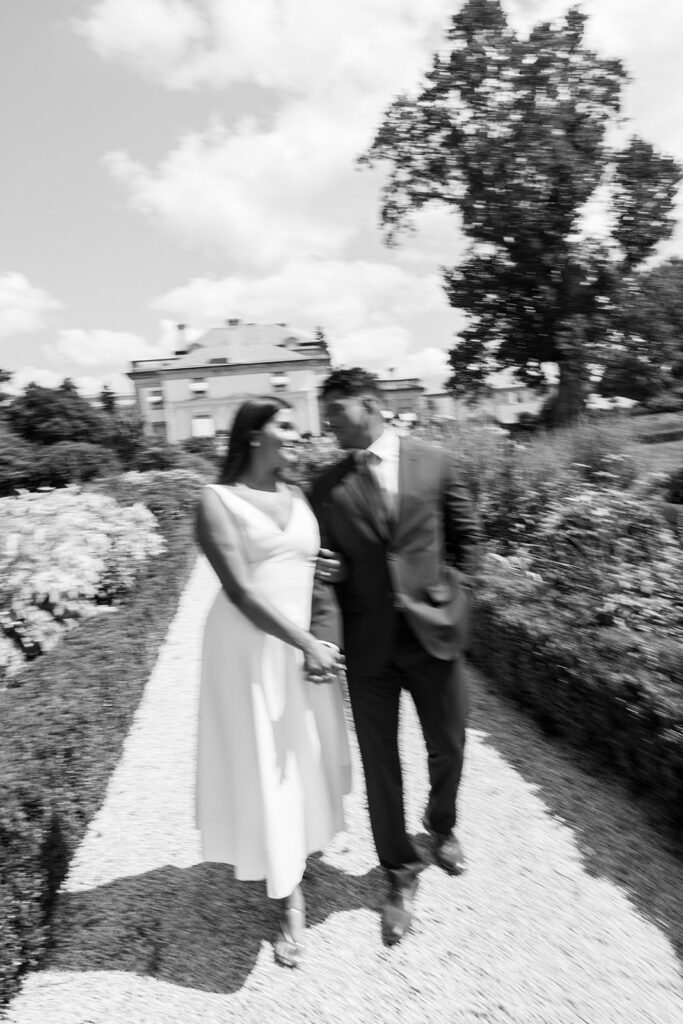 Nemours Estate engagement session black and white motion blur couple walking through garden path with Nemours mansion in background Delaware