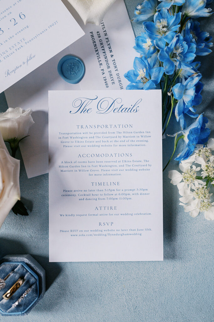 Blue and white wedding invitation details card for a summer Elkins Estate wedding, styled with delphinium and a wax seal