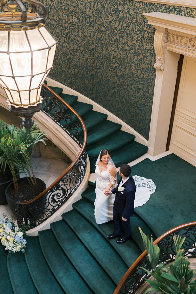 Bride and groom walk together down a grand green staircase at Elkins Estate wedding venue in Philadelphia, photographed by Lindsey Ford