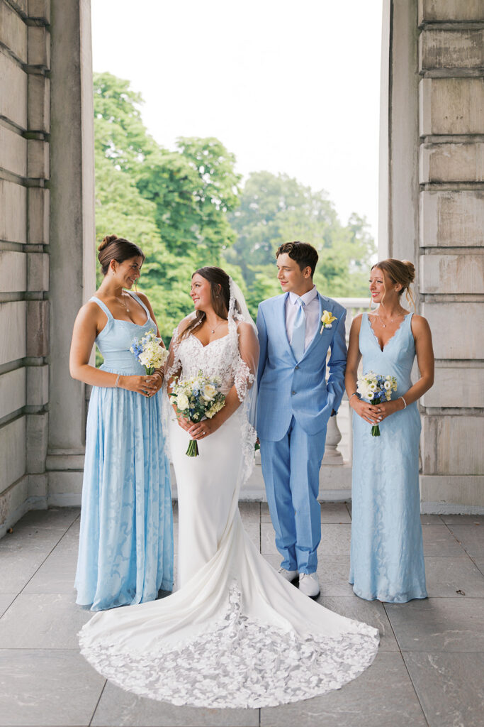 Bride stands with her three bridal party attendants in light blue attire